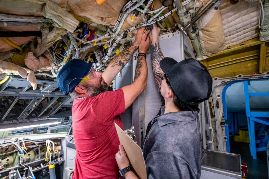An aircraft test technician trainee (left) practices working on a section of fuselage from a retired 737 alongside an employee development specialist at Boeing’s Foundational Training Center in Renton, Wash.