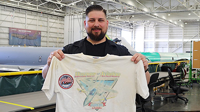 KC-46A modification electrician Chris Beers holds up a white shirt from the Museum of Aviation in Georgia.